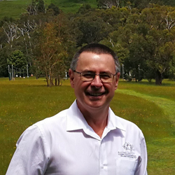 A picture of Rod Thomson, the CEO of the Australian Camps Association and People Outdoors. He is smiling with a green landscape in the background.